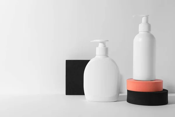 Bottles with different cosmetic products and podiums on white background, space for text