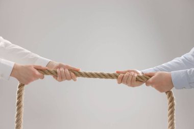Tartışma konsepti. Açık gri arka planda ipi çeken adamlar, yakın plan.