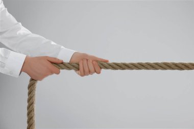 Tartışma konsepti. Açık gri arka planda ipi çeken adam, yakın plan.