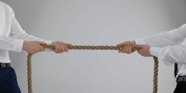 Tartışma konsepti. Açık gri arka planda ip çeken adamlar, yakın plan. Metin için boşluk