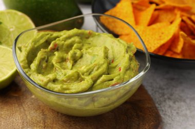 Masada cips ve limonla servis edilen bir kase lezzetli guacamole.