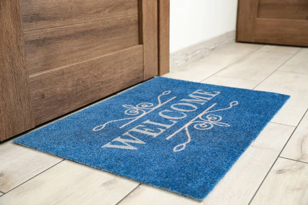 Stock image Beautiful blue doormat with word Welcome on floor near entrance