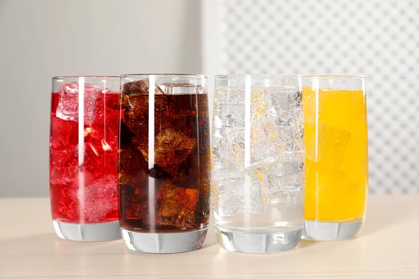 Gläser Mit Verschiedenen Erfrischungsgetränken Mit Eiswürfeln Auf Weißem Tisch — Stockfoto
