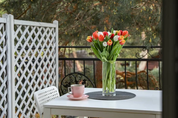 Piękne Kolorowe Tulipany Szklanym Wazonie Filiżanka Napoju Białym Stole Balkonie — Zdjęcie stockowe