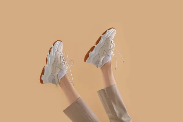 Bej Arka Planda Bir Çift Şık Spor Ayakkabı Giyen Kadın — Stok fotoğraf