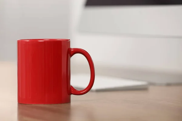 stock image Red ceramic mug on wooden table at workplace. Space for text