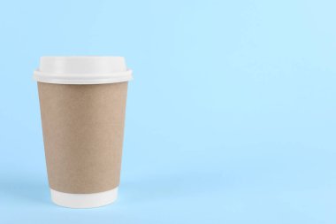 Açık mavi arka planda plastik kapaklı kağıt bardak, metin için boşluk. Kahve hazır.