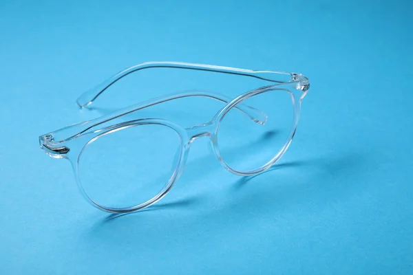 ライトブルーの背景にスタイリッシュなフレームのメガネ — ストック写真