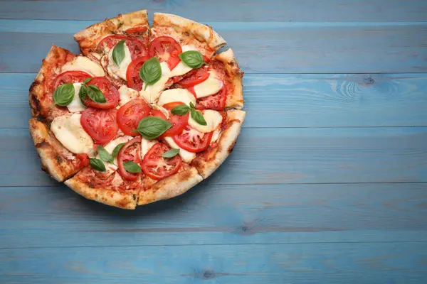 Lezzetli Caprese pizzası, mavi ahşap masa, üst manzara. Metin için boşluk