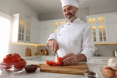 Beyaz mermer masada domates kesen profesyonel bir aşçı.