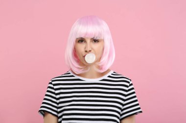 Güzel bir kadın pembe arka planda sakız üflüyor