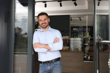 Kafesinin kapısında mutlu bir işyeri sahibi var. Metin için boşluk