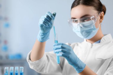 Bilim adamı laboratuardaki test tüpünden numune alıyor.