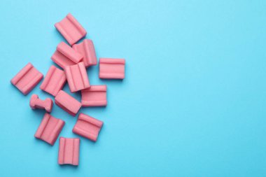 Açık mavi arka planda leziz pembe sakızlar, düz uzanış. Metin için boşluk