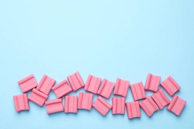 Açık mavi arka planda leziz pembe sakızlar, düz uzanış. Metin için boşluk