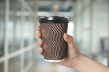 Paket kahve. Arka planda kağıt bardak sıcak içecek tutan kadın, yakın plan.