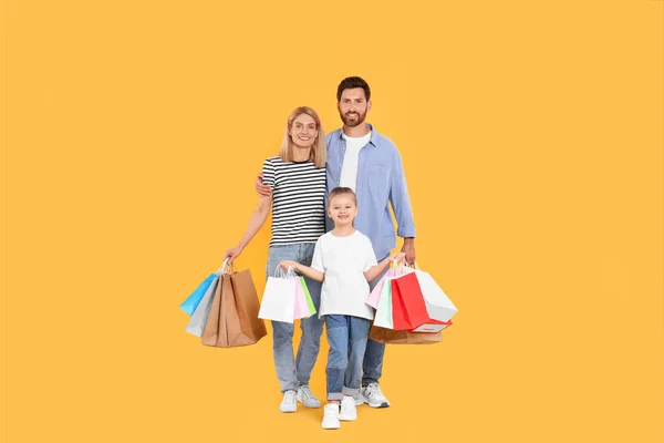 家庭购物 快乐的父母和女儿 带着橙色背景的纸袋 — 图库照片