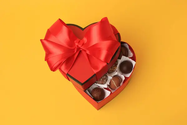 有黄色背景的美味巧克力糖果的心形盒子 — 图库照片