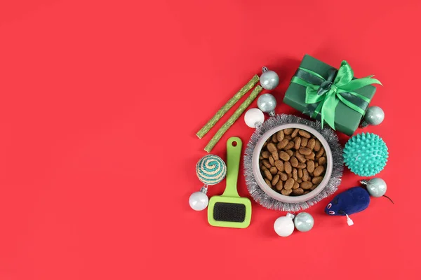 Different pet goods with Christmas gift on red background, flat lay and space for text. Shop assortment