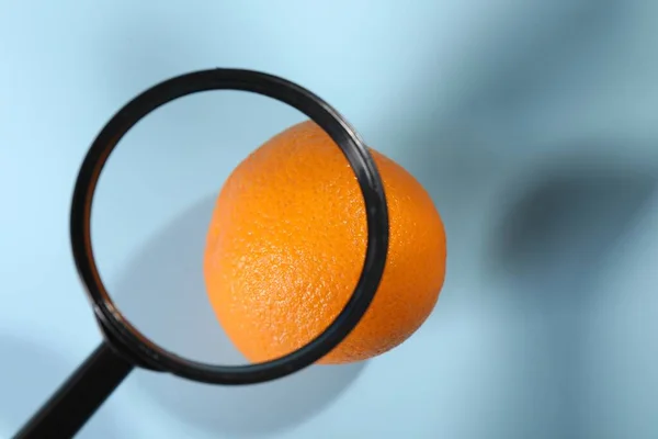 Cellulite problem. Zoomed orange peel on light blue background, top view through magnifying glass