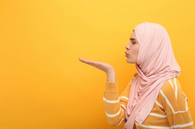Turuncu arka planda öpüşen tesettürlü Müslüman kadın, mesaj için boşluk