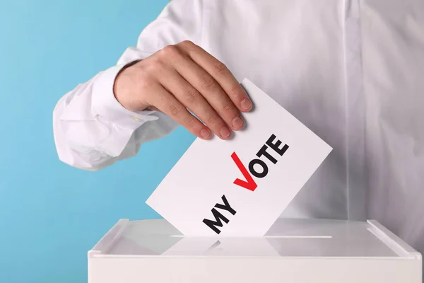 男はテキストで紙を置く 私の投票し ライトブルーの背景に投票箱にチェック — ストック写真
