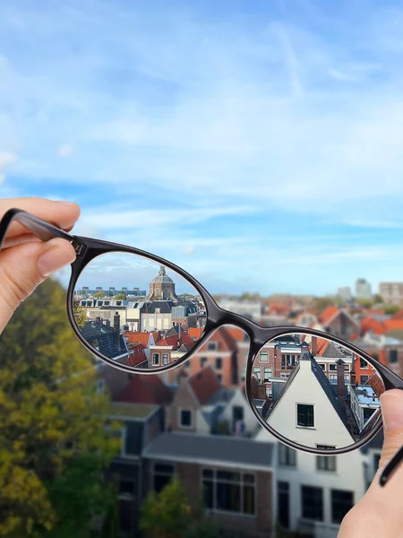 Vision correction. Woman looking through glasses and seeing cityscape clearer