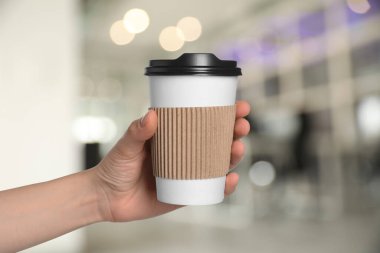 Paket kahve. Arka planda kağıt bardak sıcak içecek tutan kadın, yakın plan.