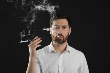 Siyah arka planda sigara içmek için uzun sigara tutacağı kullanan adam.