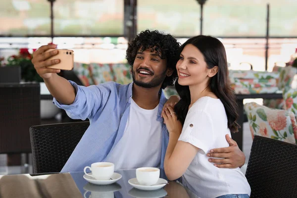 International dating. Happy couple taking selfie in restaurant