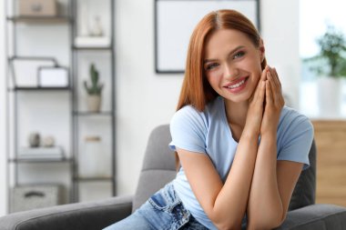 Evinde kızıl saçlı güzel bir genç kadının portresi. Gülümseyen ve kameraya bakan çekici bir kadın. Metin için boşluk