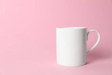 Pembe arka planda beyaz bir seramik bardak. Metin için boşluk