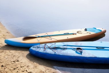 SUP boards with paddles on river shore