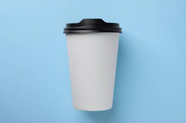 Açık mavi arka planda bir kağıt bardak, üst manzara. Kahve hazır.