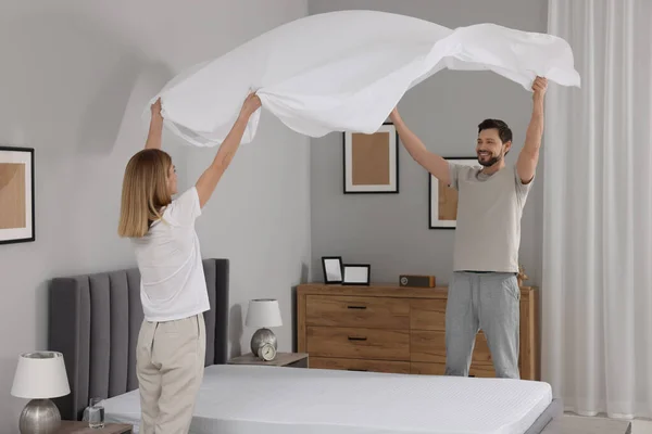 stock image Couple changing bed linens in room. Domestic chores