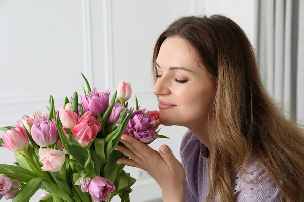 屋内で美しいチューリップの花束を嗅ぐ女性 — ストック写真