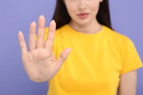 Woman showing stop gesture on violet background, closeup. Space for text