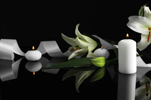 暗闇の中で黒い鏡面に白いユリと燃えるろうそく テキストのためのスペース 葬儀のシンボル — ストック写真