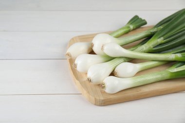 Taze yeşil taze soğanlar beyaz ahşap masada, yakın plan. Metin için boşluk
