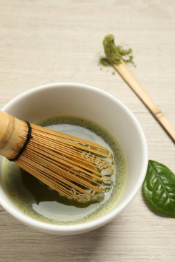 Bir fincan taze yeşil kibrit çayı bambu çırpıcı ve kaşık ile ahşap masa, yakın çekim