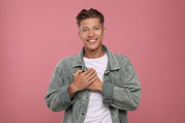 Teşekkür ederim. Pembe arka planda elleri göğsünde olan yakışıklı bir adam.