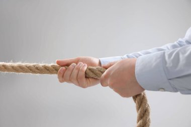 Tartışma konsepti. Açık gri arka planda ipi çeken adam, yakın plan.