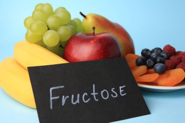 Kelime Fructose, lezzetli olgun meyveler, böğürtlenler ve açık mavi arka planda kurutulmuş kayısılar, yakın plan