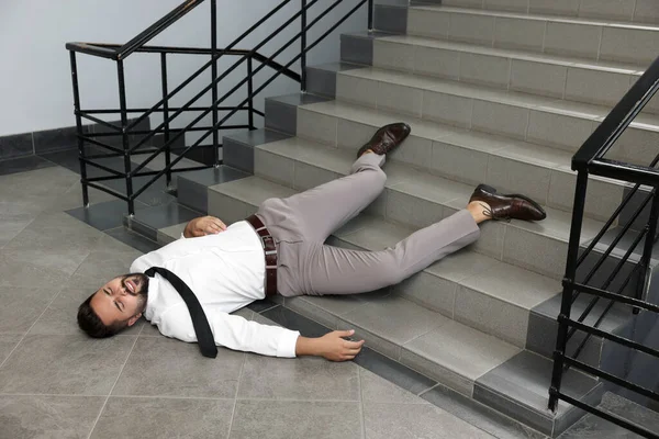 Unconscious man lying after falling down stairs indoors