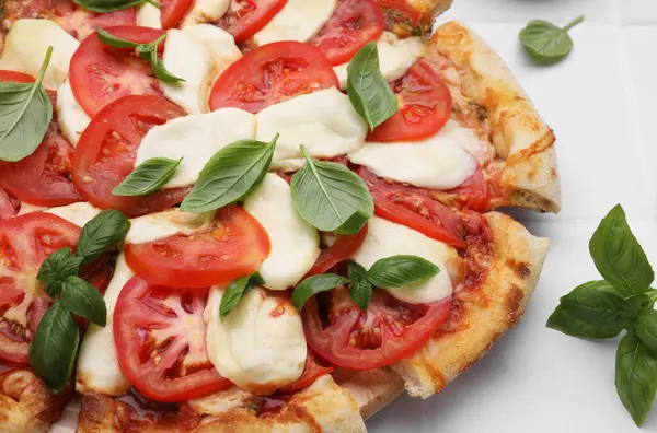 Domatesli lezzetli Caprese pizzası, mozzarella ve fesleğen beyaz masada, yakın plan.