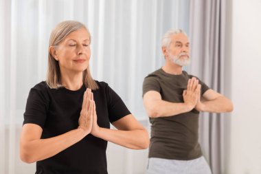 Yaşlı çift evde yoga yapıyor, seçici odaklanma.