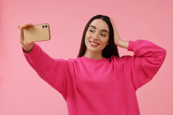 Uśmiechnięta Młoda Kobieta Robi Selfie Smartfonem Różowym Tle Miejsce Tekst — Zdjęcie stockowe