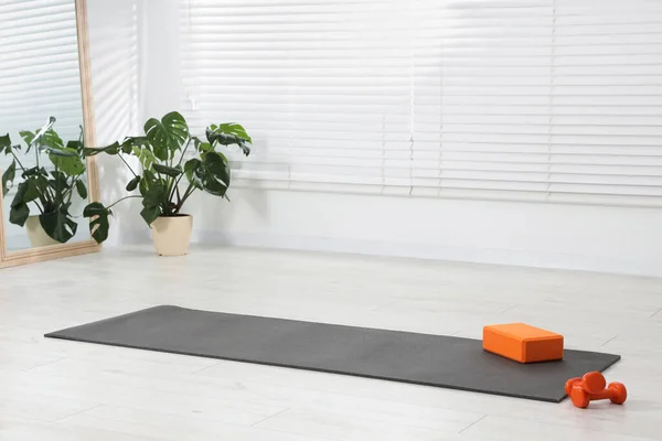 Exercise mat, yoga block and dumbbells at home. Space for text