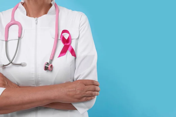 博士与粉红带和听诊器浅蓝色背景 特写和文字空间 乳腺癌意识 — 图库照片