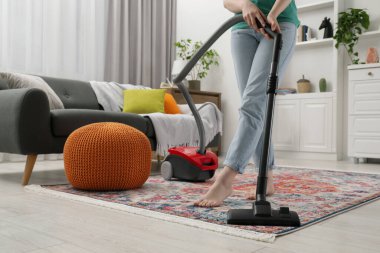 Halıyı elektrikli süpürgeyle temizleyen kadın, yakın çekim.